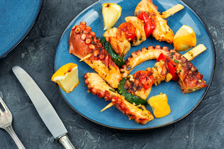 Grilled octopus on wooden skewers on blue plate. Grilled seafood.の写真素材