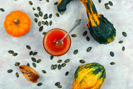 Homemade autumn pumpkin or squash jam in a jar and fresh pumpkins. Top view.の写真素材