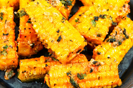 Delicious baked corn with spices and herbs. Healthy vegetarian food, close-up.