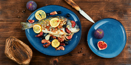 Baked gilt head bream, dorado fish with almonds and figs on rural wooden table. Autumn recipe.の写真素材