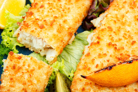Pollock fillet roasted in bread crumbs and with kiwi. Close up.