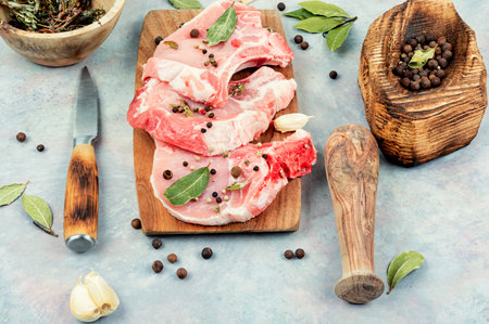 Raw pork steak in spices on a wooden board.の写真素材