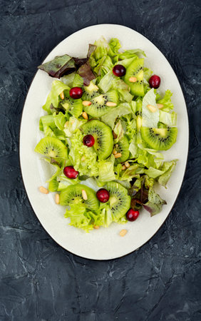 Delicious fresh salad of kiwi, leafy greens, berries and pine nuts. Top view.の写真素材