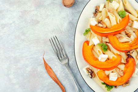 Pasta or macaroni with baked pumpkins and nuts. Autumn meal. Space for text.の写真素材