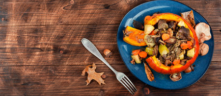 Autumn baked pumpkin stuffed with beef meat, mushrooms and carrots on wooden table. Copy space.の写真素材