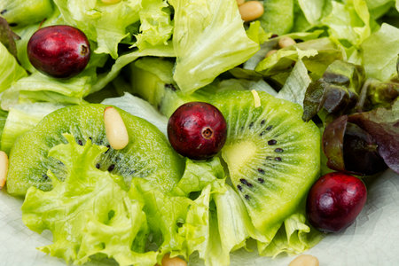 Fresh vegan salad of kiwi,mix leaves, berries and pine nuts. Close up.の写真素材