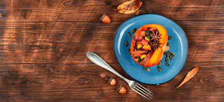 Half of the autumn pumpkin or squash baked with apples, peaches and cinnamon. Autumn food, vegan diet on old wooden background. Copy space. Space for text.の写真素材