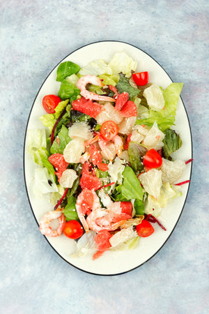 Tasty salad with pomelo, shrimps and greens. Thai appetizer salad on white plate. Vertical Photo.の写真素材