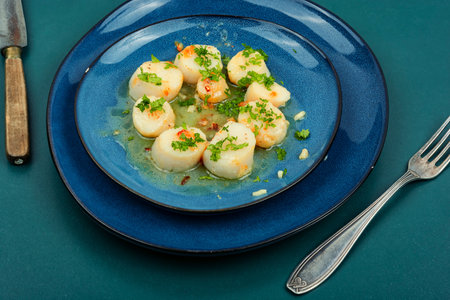 Roasted or seared scallops with green on a plateの写真素材