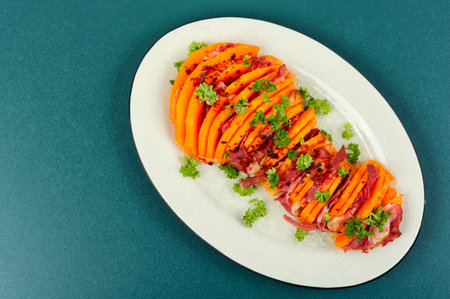 Plate with roasted pumpkin with bacon. Baked butternut squash with bacon on the table. Flat lay with...