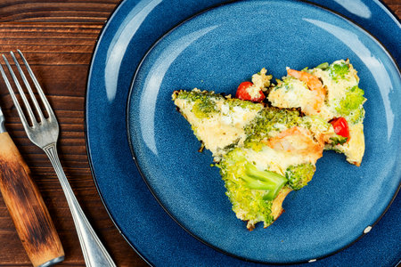Omelette with broccoli, shrimp and tomato on a rustic wooden texture.の写真素材