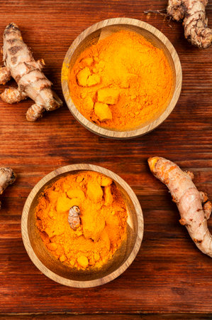 Raw turmeric root and turmeric powder on a wooden background.の写真素材