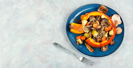 Autumn roasted pumpkin stuffed with beef meat, mushrooms, apple and carrots. Copy space.の写真素材