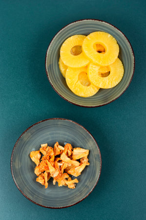 Dry and fresh pineapples in bowls. Candy pineapples, candied fruits. Fruit snack.の写真素材