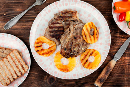 Tasty grilled meat,roasted with pineapple on wooden table. Grilled steak and ananas. Top view.の写真素材