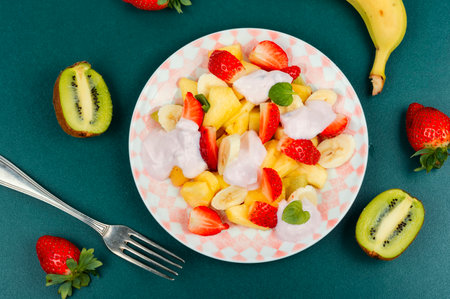 Fruit salad of pineapple, strawberries,banana, kiwi and sweet yogurt on a plate. Flat lay.の写真素材