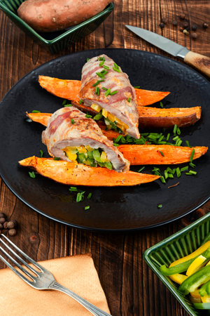 Homemade meat tenderloin or meat roll served with baked sweet potatoes on old rustic wooden table.の写真素材