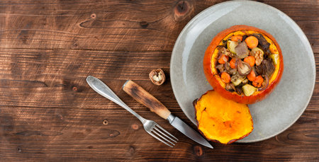 Autumn baked pumpkin stuffed with beef meat, mushrooms and carrots on wooden table. Copy space.の写真素材