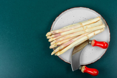 Uncooked fresh white asparagus on the kitchen table. Seasonal spring vegetables. Top view, copy space.の写真素材