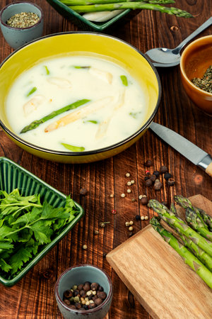 Homemade vegetarian soup with white and green asparagus on rustic wooden table.の写真素材
