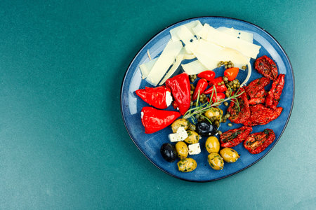 Greek appetizer of sun-dried tomatoes, black and green olives and stuffed cheese with marinated red peppers. Copy space.の写真素材
