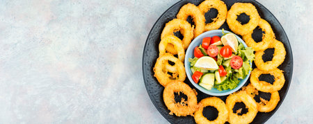 Serving of calamari, deep-fried squid rings, garnished with vegetable salad and served on a plate. Free space for your text.の写真素材