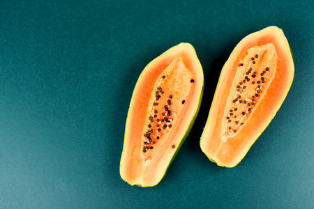 Sliced fresh juicy papaya on the table. Ripe papaya fruit cut in half. Space for text.