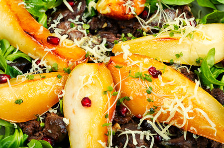 Warm autumn salad greens leaves,chicken liver, caramelized pear. Close up.の写真素材