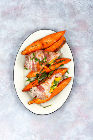 Stuffed pork roast or roulade with roasted vegetables and baked sweet potato.の写真素材