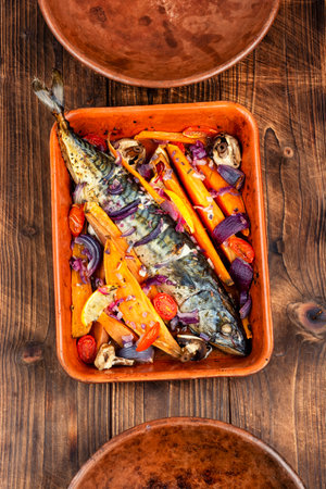 Fried or baked mackerel fish with lemon, sweet potato fries and spices on rustic wooden table.の写真素材