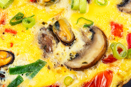 A delicious mussels omelette or frittata garnished with vegetables. Protein appetizing tasty nutrition food. Close upの写真素材