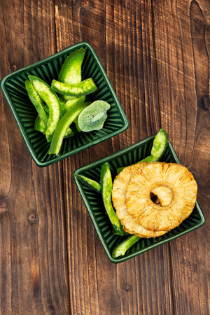 Sweets candied fruits from kiwi slices , mango slices and pineapple rings, dried exotic fruits on rustic wooden table.の写真素材