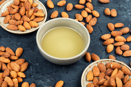 Almond nuts peeled roasted. Natural almond oil in bowl and nuts on a table.の写真素材