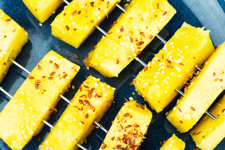 Ripe tropical fruit pineapple on skewers, fruit shashlik. Fruit kebabs with sesame seeds. Close up,macroの写真素材
