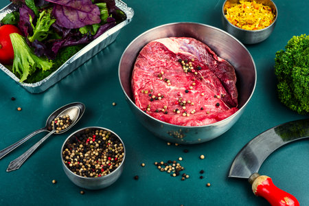 Uncooked piece of raw and fresh beef with ingredients for cooking.の写真素材