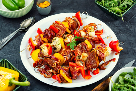 Skewers with pieces of raw meat, mushrooms, yellow and green bell pepper.の写真素材