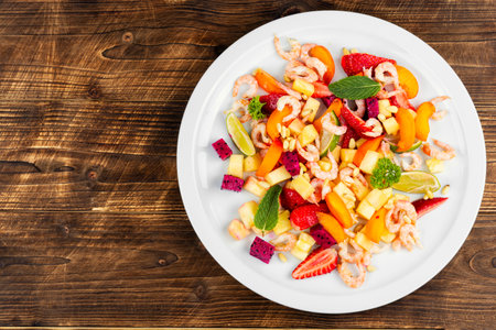Delicious salad with shrimps, pineapple, apricots, dragon fruit and pine nuts.の写真素材