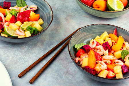 Colorful and fresh seafood salad plate with shrimps, pineapple, apricots, dragon fruit and pine nuts.の写真素材
