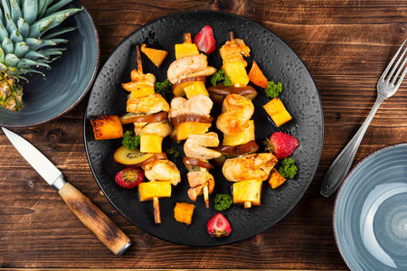 Wooden skewers with grilled chicken fillet and pineapple. Platter of grilled meat skewers featuring vibrant and juicy pineappleの写真素材
