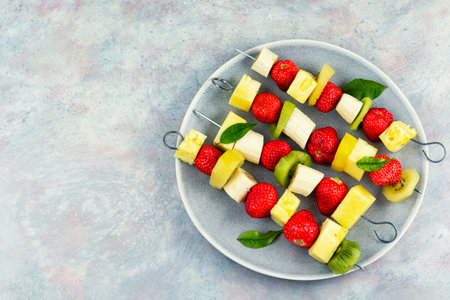 Fresh fruit skewers with strawberries, banana, kiwi, and pineapple, healthy snack. Copy space.の写真素材