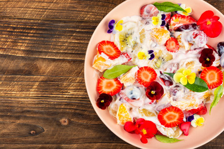 Summer salad of mixed fruits with white yogurt and flowers. Healthy food. Copy space.の写真素材