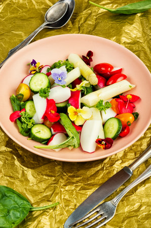 Vegetable salad decorated with edible flowers with white asparagus. Vegan cuisine.の写真素材