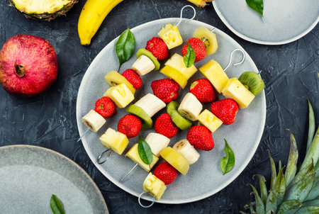 Assorted fresh fruits on skewers, raw banana, pineapple, fresh strawberry and kiwi. Flat lay.の写真素材