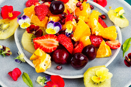 Bowl or plate filled with fresh fruits, delicious mixed fruit salad garnished edible flowers.