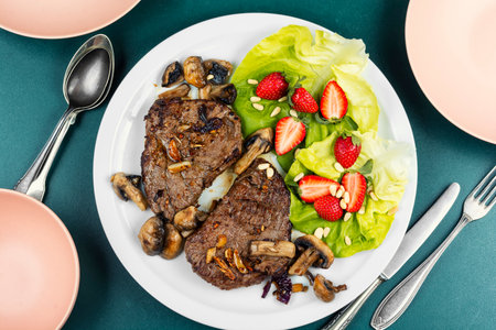 Aromatic roasted veal and beef steak with a garnish of fresh strawberries and lettuce. Flat lay.の写真素材