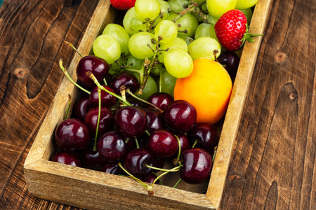Plates with fresh fruits and berries in box on wooden surface.の写真素材
