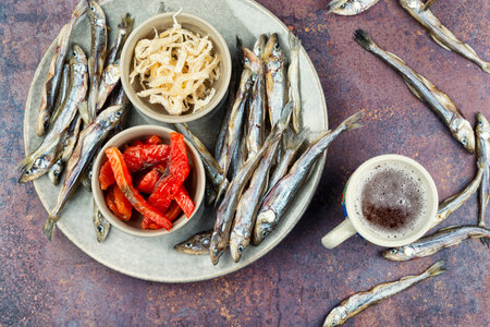 Beer and a set of dry fish snacks, unfiltered beer and with dried fish pieces and squid. Overhead view.の写真素材