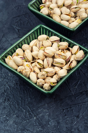 Salted pistachios served on a plate against on a concrete kitchen table. Minimal food composition.