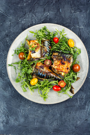 Roasted mackerel pieces with fresh salad greens, and cherry tomatoes. Baked fish with herbs.の写真素材
