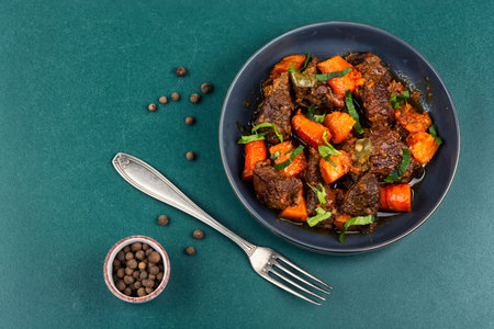 Slow braised beef chunks with roasted sweet potatoes in rich savory sauce, served in a bowl. Top view. Copy space.の写真素材